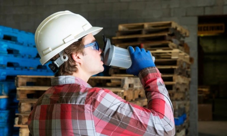 Warehouse worker drinking from reusable water bottle
