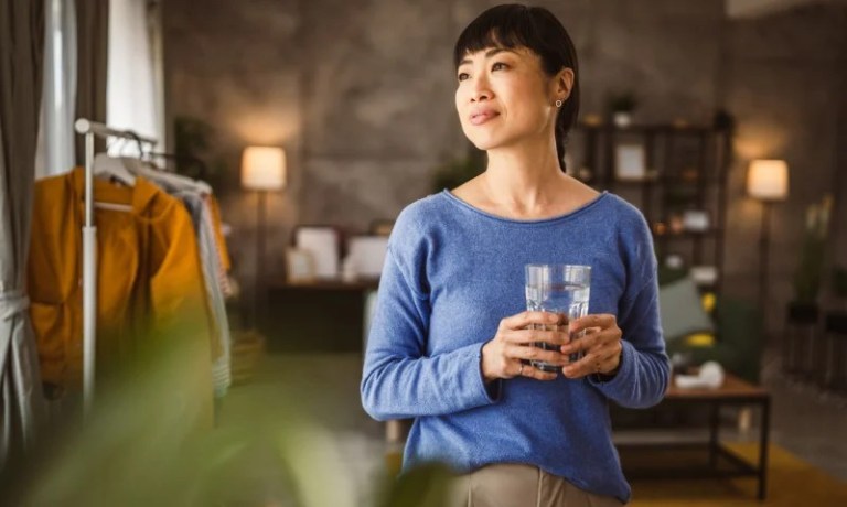 Retail employee at clothing store holding glass of water