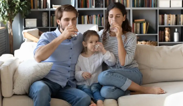 Family sitting on a couch drinking water